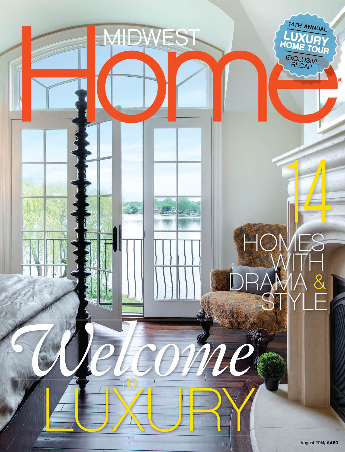 Midwest Home Magazine Cover for August 2014 with a luxury bedroom showing the end of a bed with a tall ornate bedpost and stone fireplace at the foot of the bed with white French doors opening up to a view of the lake. Th floors are dark oak and there is a light brown chair in the corner of the room.